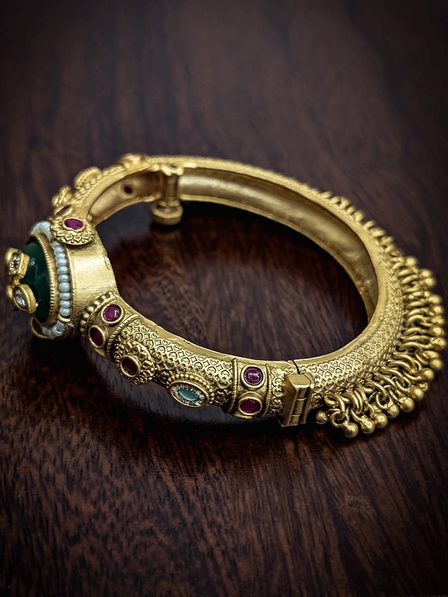 Oval coloured stone in center of single openable kada with kundan studded inlay work on stone and ghunghru hangings