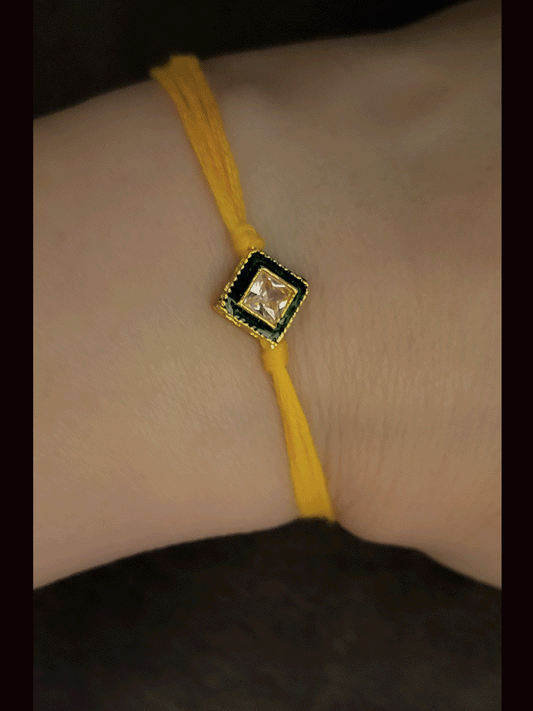 Square shaped brown stone with green enamel outline bhai rakhi in yellow thread