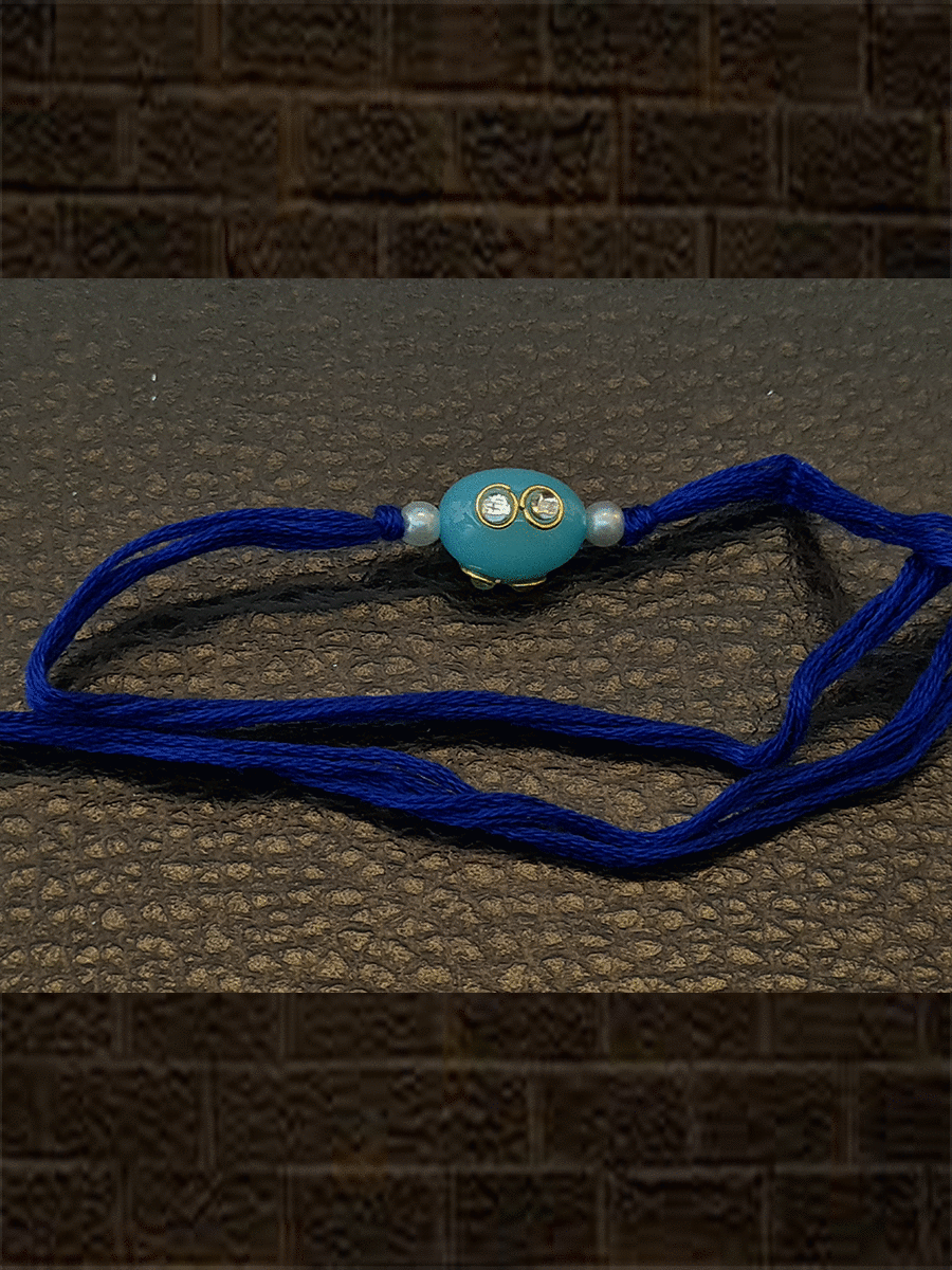 Oval blue glass bead kundan with side pearl rakhi in dark blue thread - Odara Jewellery