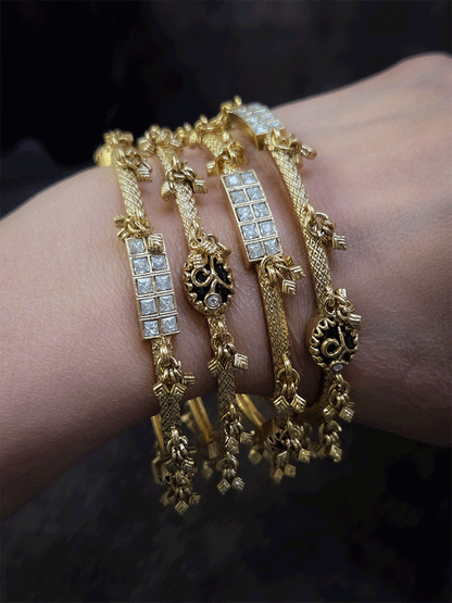 Set of four non-openable ghunghru hanging bangles with inlay work on oval green stone