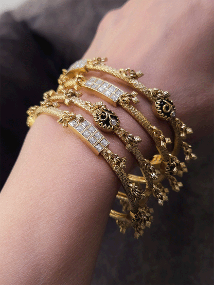 Set of four non-openable ghunghru hanging bangles with inlay work on oval green stone