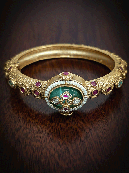 Oval coloured stone in center of single openable kada with kundan studded inlay work on stone and ghunghru hangings