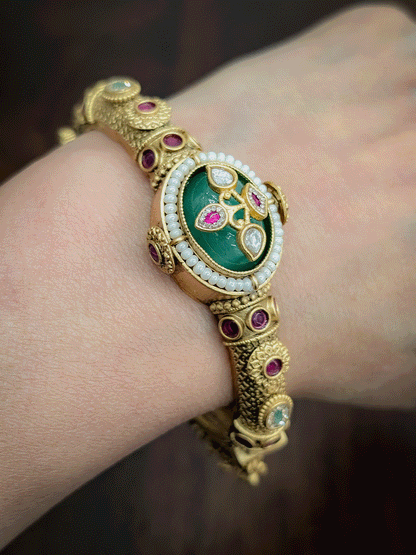 Oval coloured stone in center of single openable kada with kundan studded inlay work on stone and ghunghru hangings