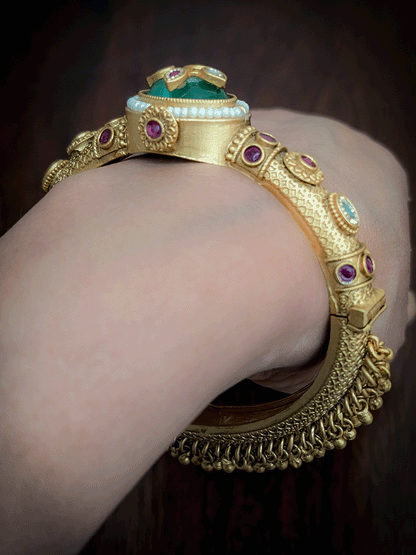Oval coloured stone in center of single openable kada with kundan studded inlay work on stone and ghunghru hangings