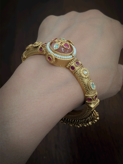 Oval coloured stone in center of single openable kada with kundan studded inlay work on stone and ghunghru hangings