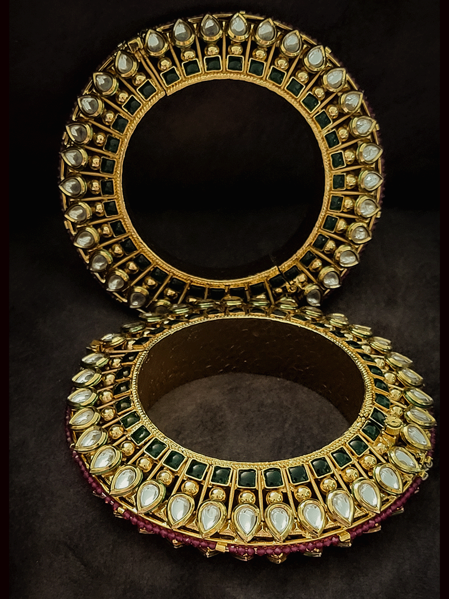 Set of two tear drop shaped kundan kada's with green stones line on the sides with ruby beads pirohi openable pacheli's