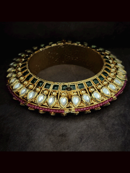 Set of two tear drop shaped kundan kada's with green stones line on the sides with ruby beads pirohi openable pacheli's