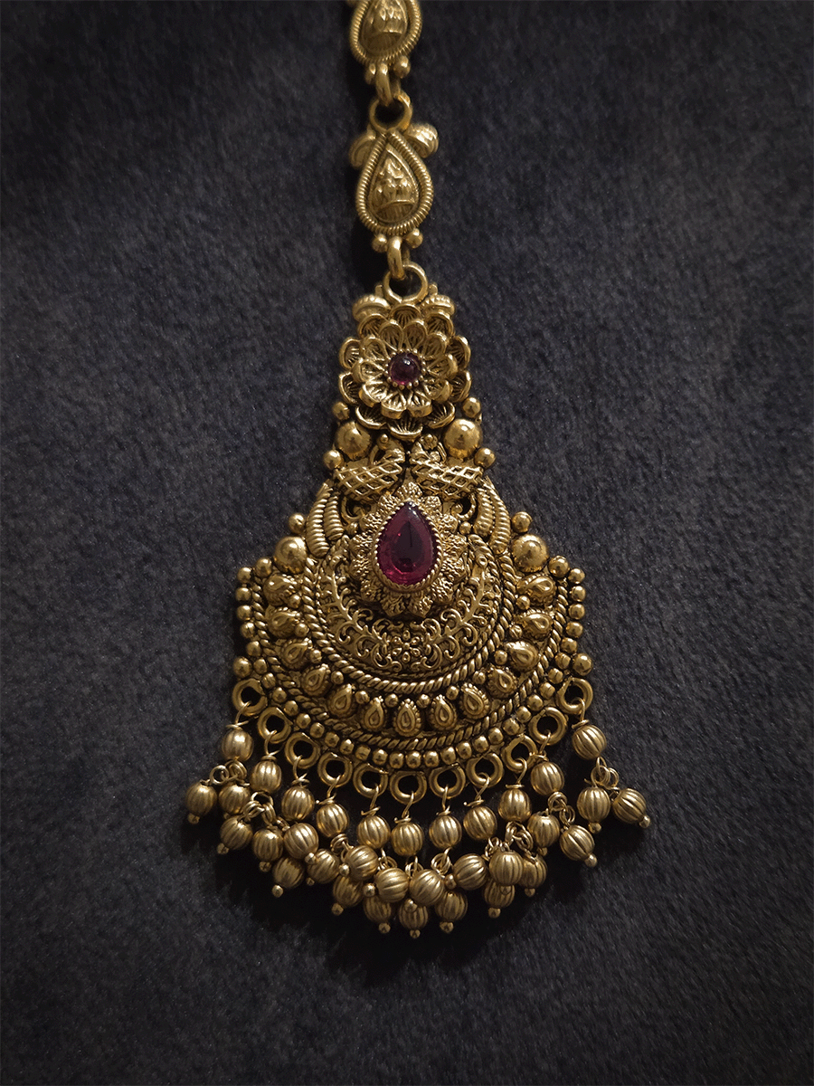 Tear shaped ruby stone center with flower top design maangtika with gold bead hangings
