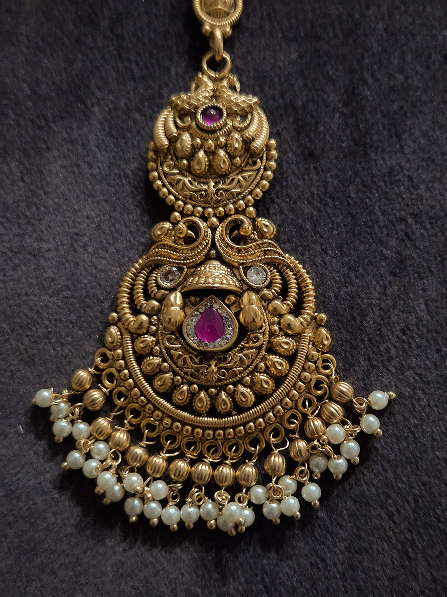 Peacock top circular design with tear drop shaped ruby stone in center of bottom design maangtika