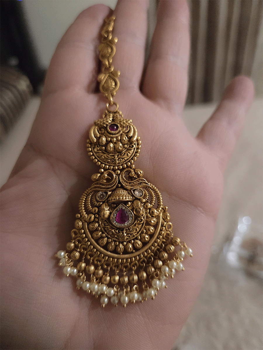 Peacock top circular design with tear drop shaped ruby stone in center of bottom design maangtika