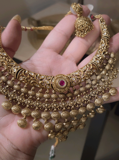 Intricately carved kundan studded hasli set with ruby stone in center and oval design tassels