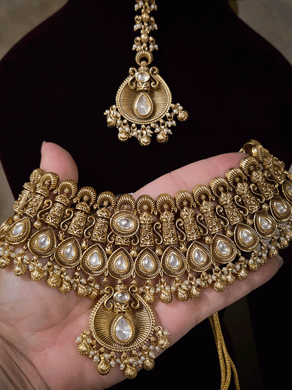 Oval kundan in center of shell ghunghru hangings intricately carved choker set with tear shaped kundan line