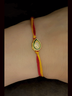 Leaf shaped brown stone with green enamel outline bhai rakhi in mauli thread