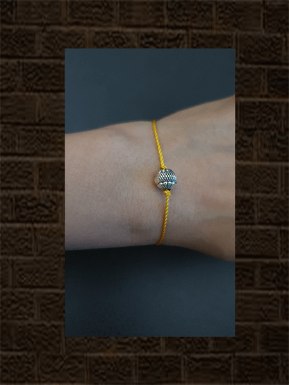 Sterling silver self design round bead rakhi in yellow thread - Odara Jewellery