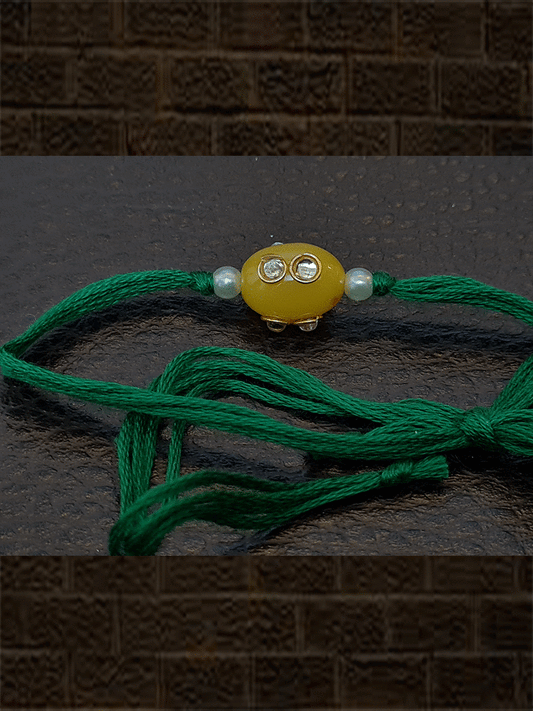 Oval yellow glass bead kundan with side pearl  rakhi in green thread - Odara Jewellery