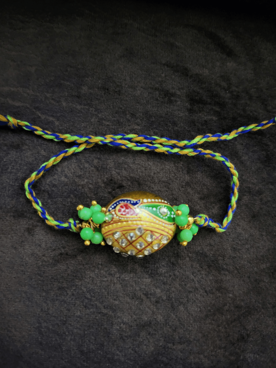 Hand painted peacock on gold bead rakhi with green bead cluster on sides - Odara Jewellery