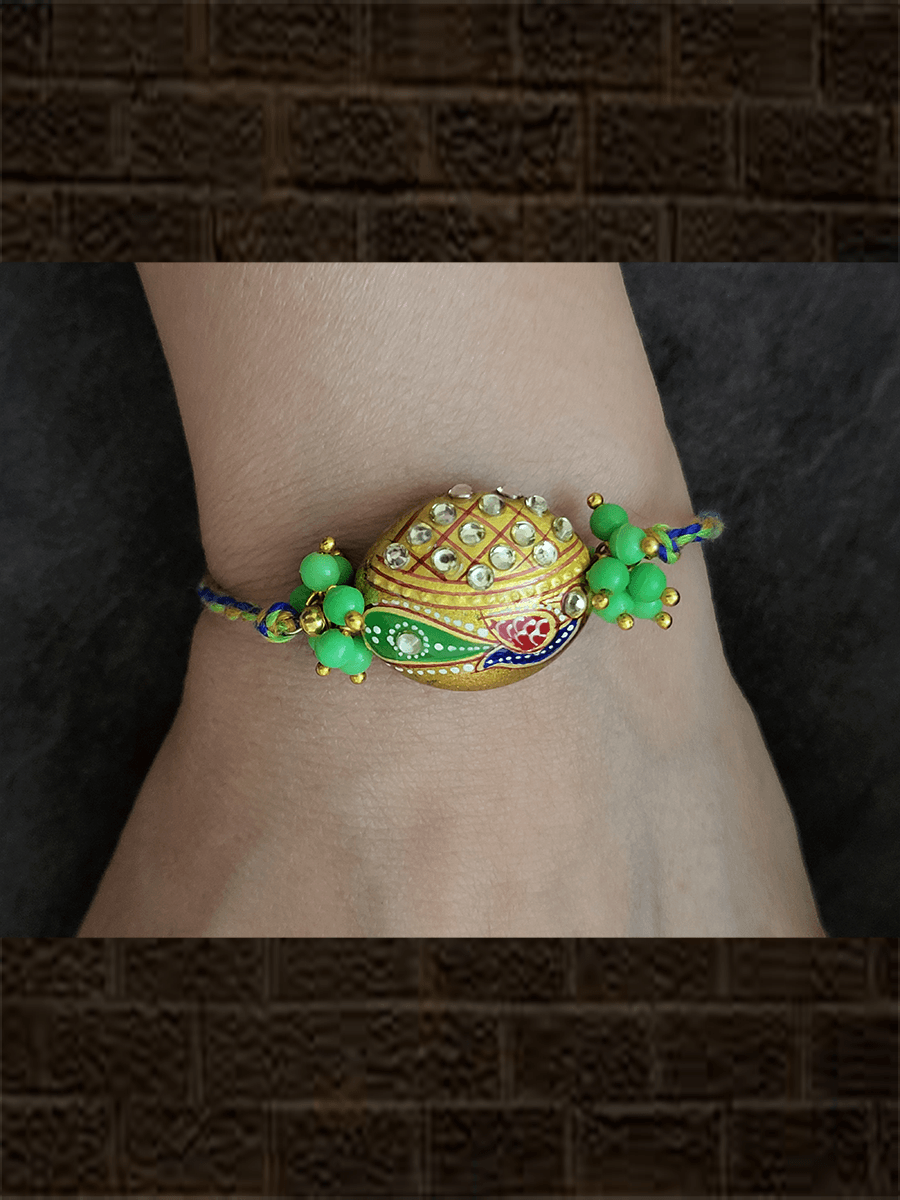 Hand painted peacock on gold bead rakhi with green bead cluster on sides - Odara Jewellery